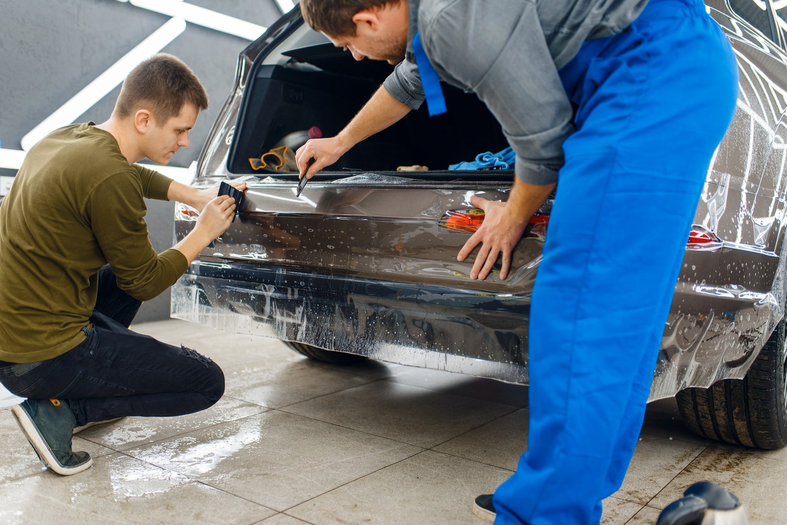 Specialists applies car protection film on bumper